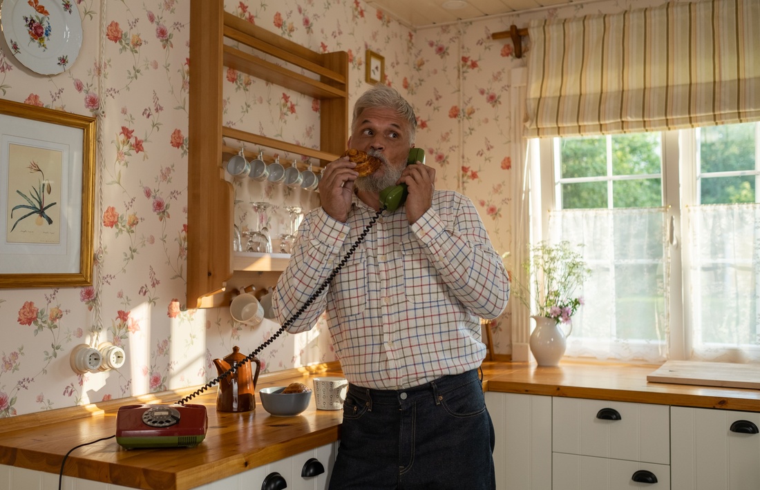 Older man speaking on a telephone at home